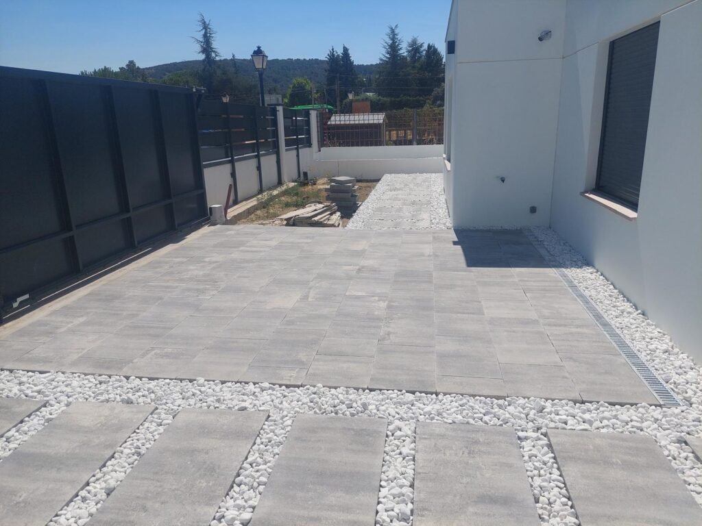 Lateral exterior con pavimento porcelánico y grava blanca, diseño limpio y mantenimiento reducido