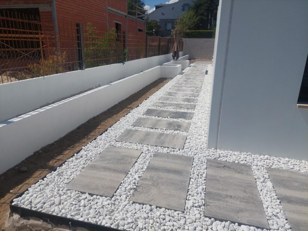 Diseño de exteriores modernos en vivienda con pavimento porcelánico y grava blanca