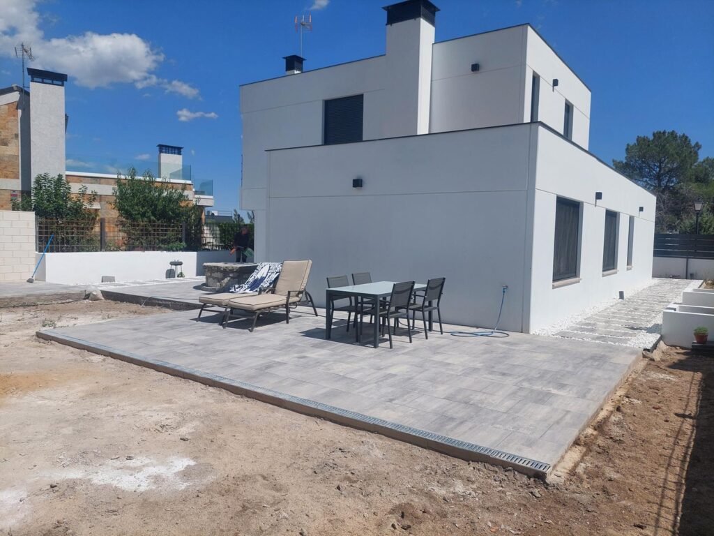 Patio exterior con pavimento porcelánico gris y grava blanca decorativa en vivienda moderna